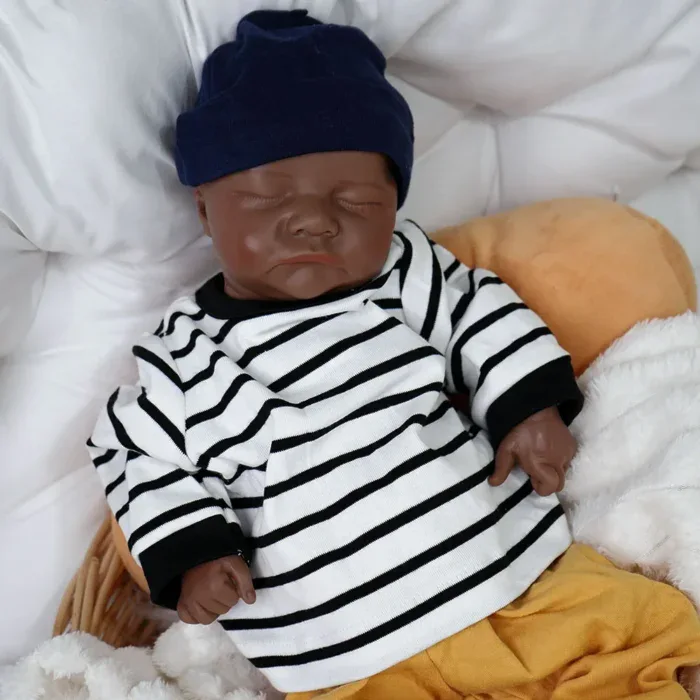 Poupée réaliste noire avec chemise rayée et chapeau bleu marine.