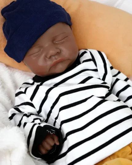 Bambola reborn realistica di Zion, un bambino nero con camicia a righe e cappello blu scuro.