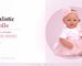 Realistic baby doll wearing pink dress and headband, sitting on pink background.