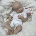 Realistic silicone reborn baby doll sleeping with bottle on soft blanket.