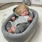 Realistic silicone reborn doll sleeping in a cozy basket.