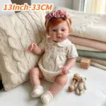 13-inch red-haired silicone reborn doll with pink headband and baby accessories.