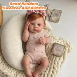 Adorable red-haired reborn baby girl doll with pink outfit and accessories.