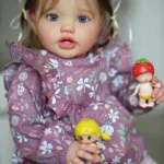 Realistic toddler girl doll with blue eyes and light brown hair holding toys.