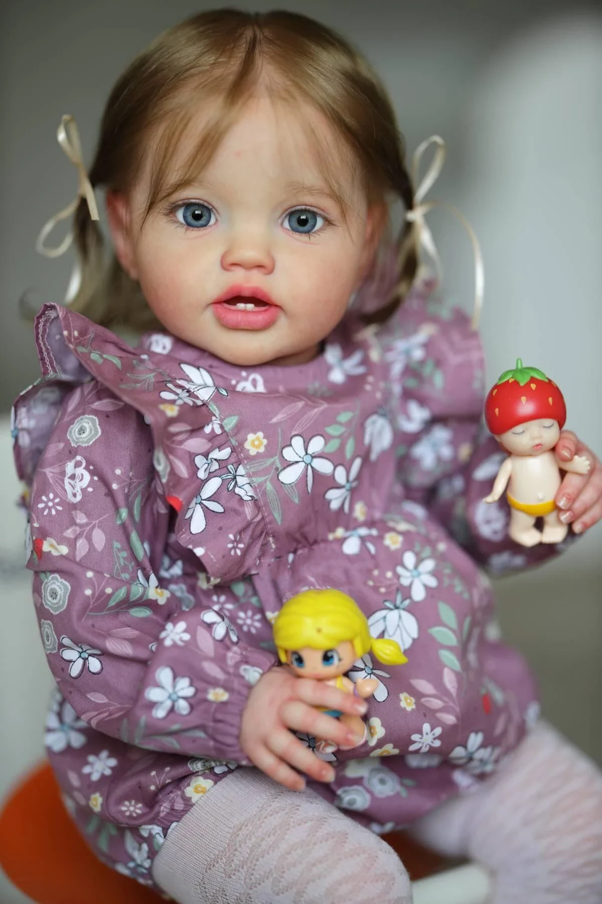 Marlowe Playful Toddler Girl Reborn Doll Realistic toddler girl doll with blue eyes and light brown hair holding toys.