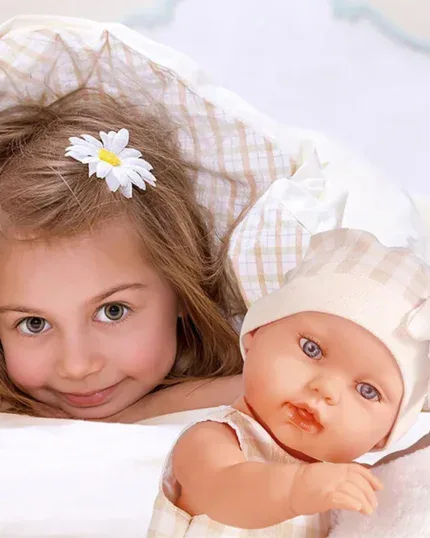 Adorable girl with a doll, both with bright eyes, lying on a bed.