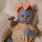 Blue-skinned reborn doll with yellow eyes and pink bow headband.