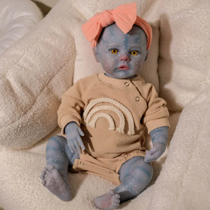 Blue-skinned girl reborn doll with yellow eyes and pink bow in hair.
