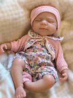 Adorable sleeping baby girl doll with pink hat and floral outfit.