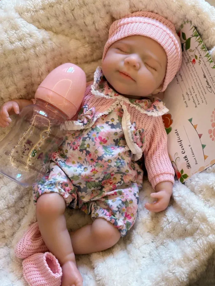 Realistic baby doll with pink hat and floral outfit, sleeping peacefully.