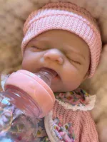 Close-up of a sleeping baby girl with a pink hat and bottle.