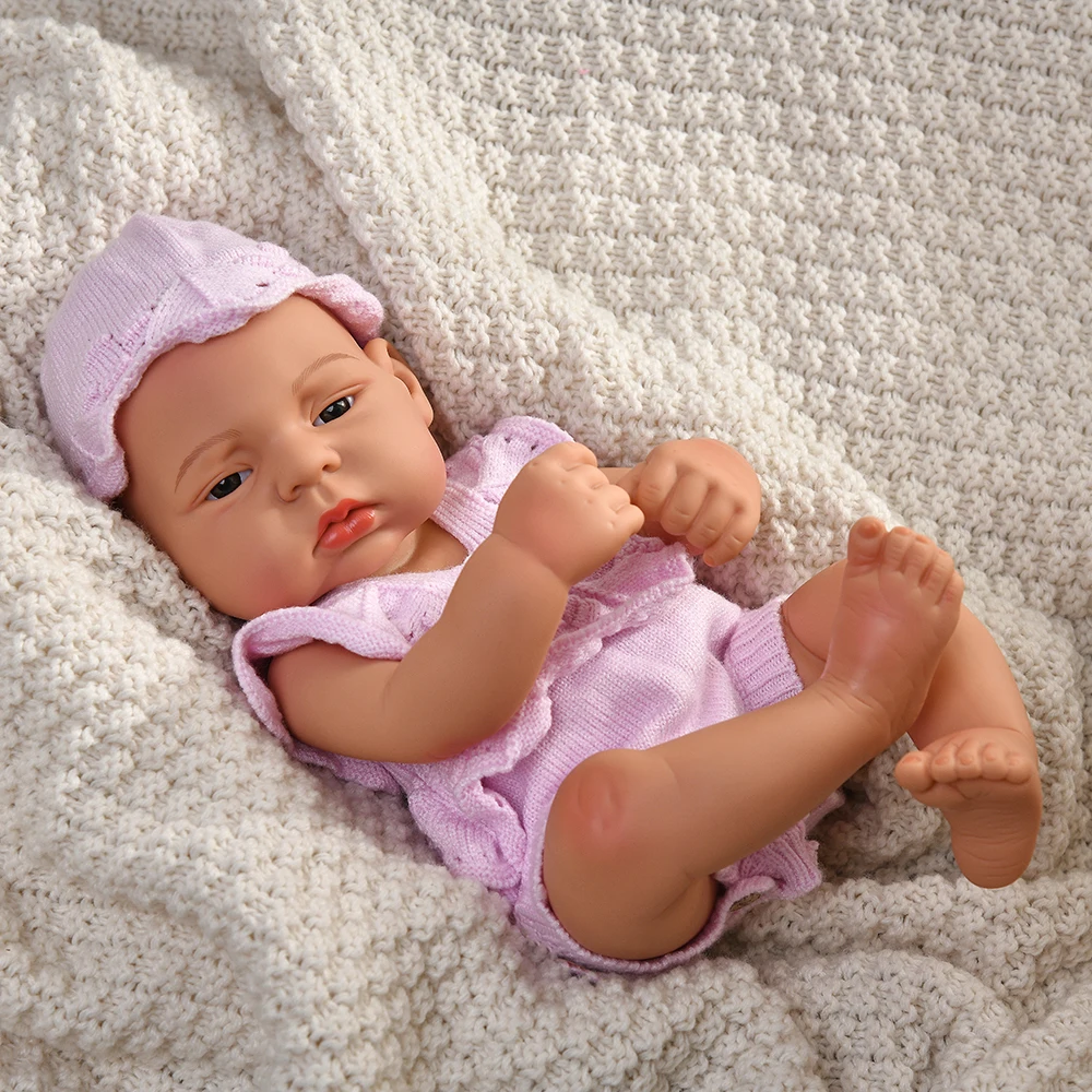 16 Inch Reborn Clothes Sweater Jumpsuit and Pinafore Set 86 Reborn baby doll wearing pink sweater and hat, lying on a cozy blanket.