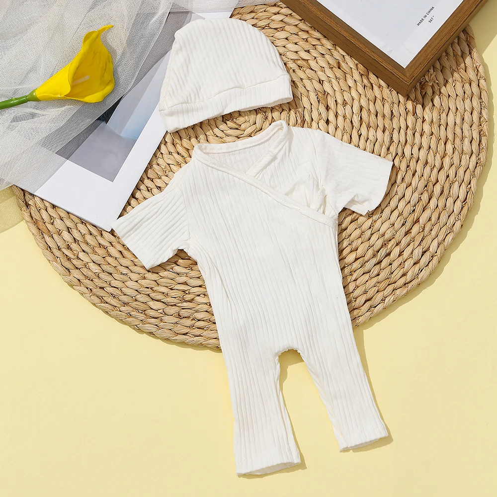 16 Inch Reborn Clothes Sweater Jumpsuit and Pinafore Set 79 White ribbed reborn baby clothes with hat on woven mat.