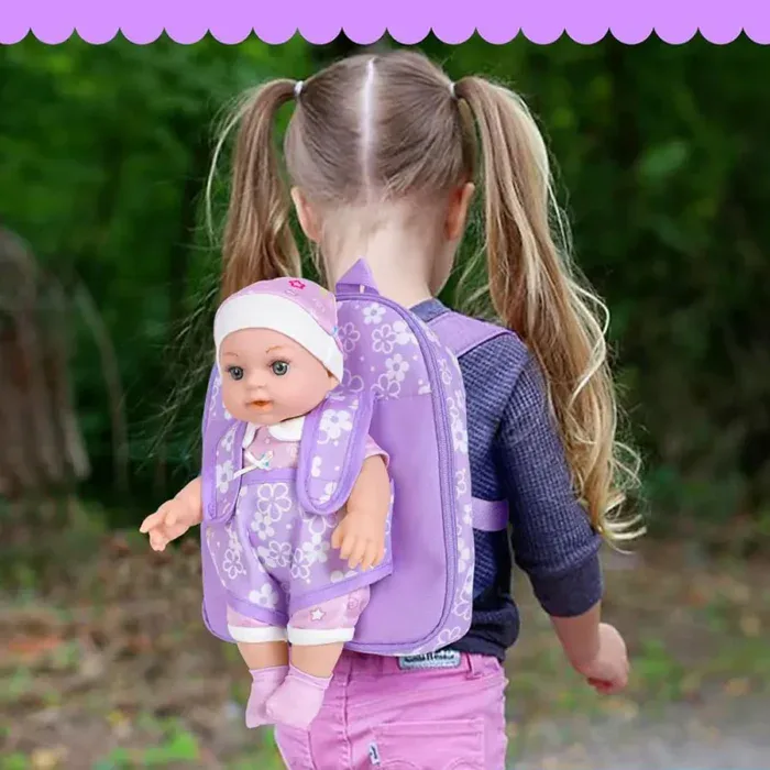 Child with purple floral doll carrier backpack outdoors.