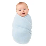 Baby wrapped in light blue cotton gauze blanket, smiling and looking at the camera.