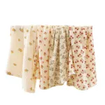 Set of four muslin doll blankets with floral and polka dot patterns.
