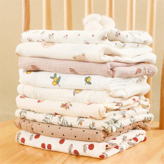 Stack of muslin doll blankets with floral and animal prints for babies.