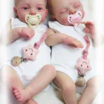 Zwei realistische Zwillingsbabypuppen mit Schnullern und Plüschtieren.