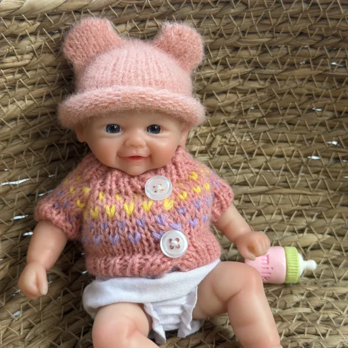Entzückende, pummelige Reborn-Babypuppe mit rosa Mütze und Pullover.