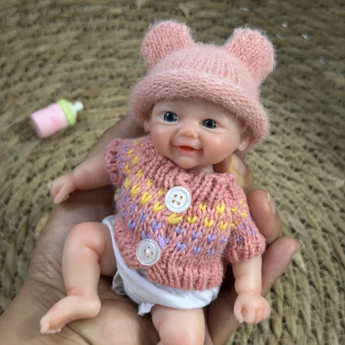 Entzückende, pummelige Babypuppe mit rosa Mütze und Strickpullover.