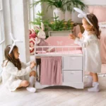 Children playing with a wooden doll crib and bunny-themed bedding.