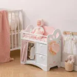 White wooden doll crib with pink bedding and plush doll, perfect for 20-inch dolls.