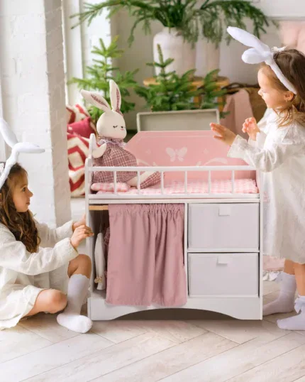 Children playing with a wooden doll crib and bunny-themed bedding.