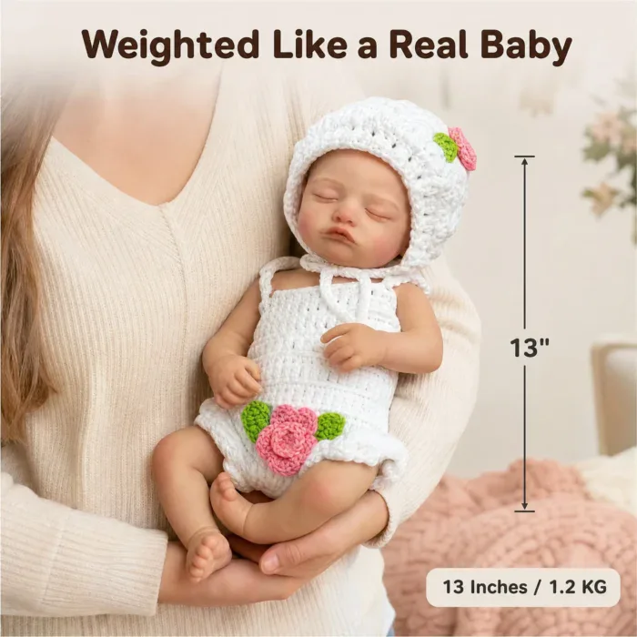 Reborn silicone baby doll in white knit outfit held gently.