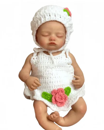 Sleeping baby girl reborn doll in white crocheted outfit with pink rose.